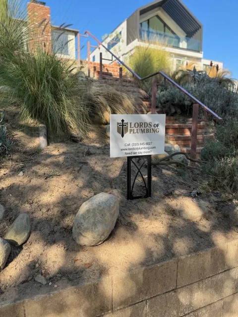 Lords of Plumbing yard sign at a hillside home job site