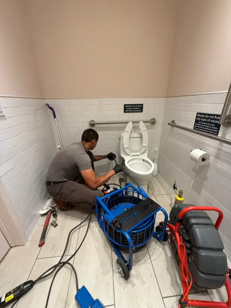 Technician servicing plumbing in a residential bathroom