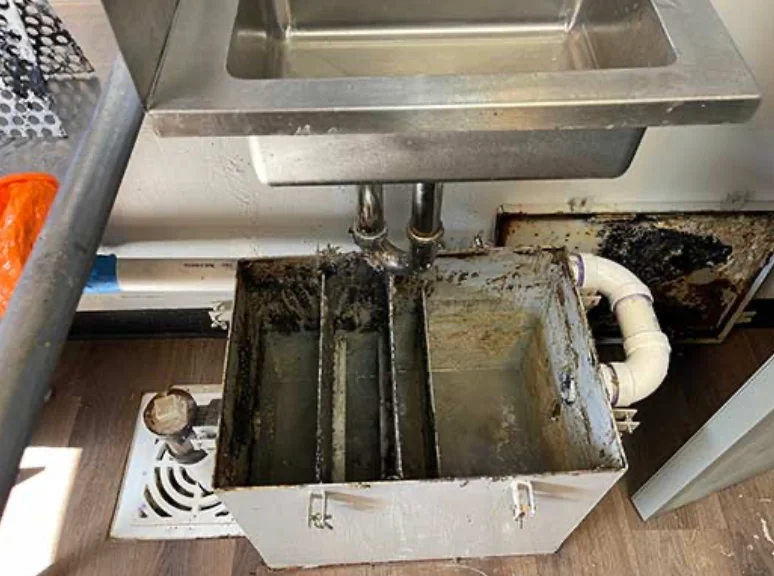 Open grease interceptor beneath a restaurant kitchen floor