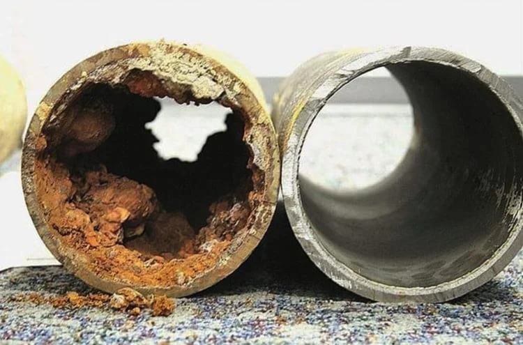 Cross-section of a corroded pipe beside a new replacement pipe